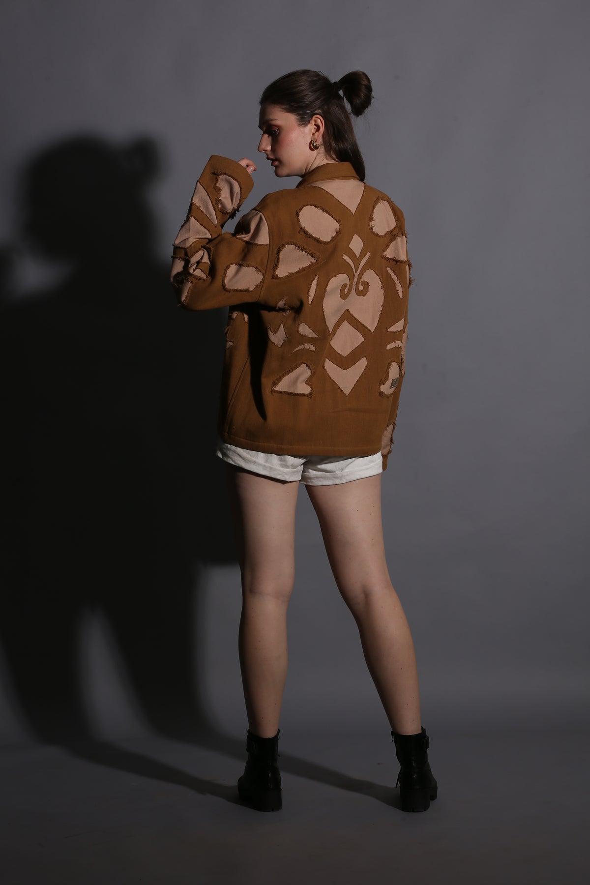Person wearing a brown patterned sweater against a dark background