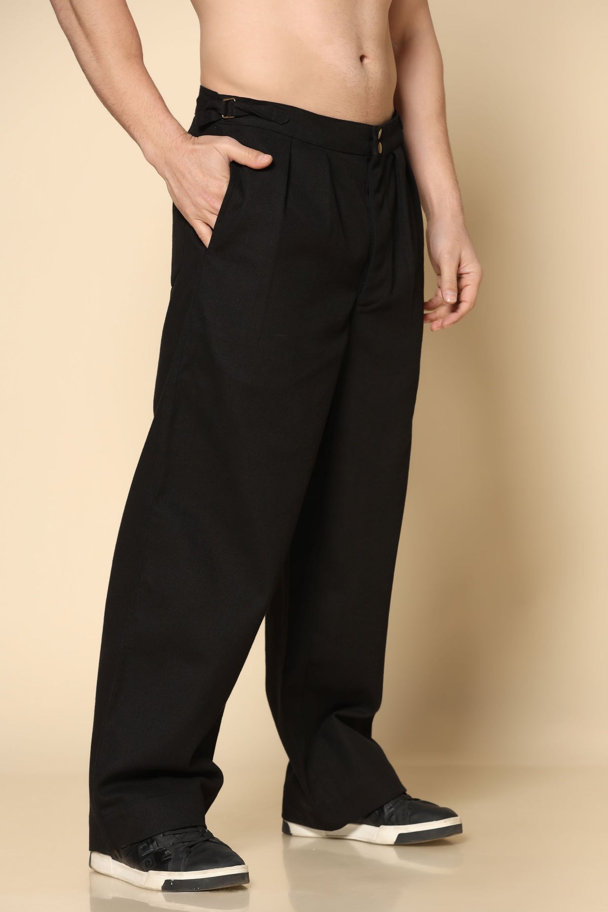 Person wearing black wide-leg pants on a beige background