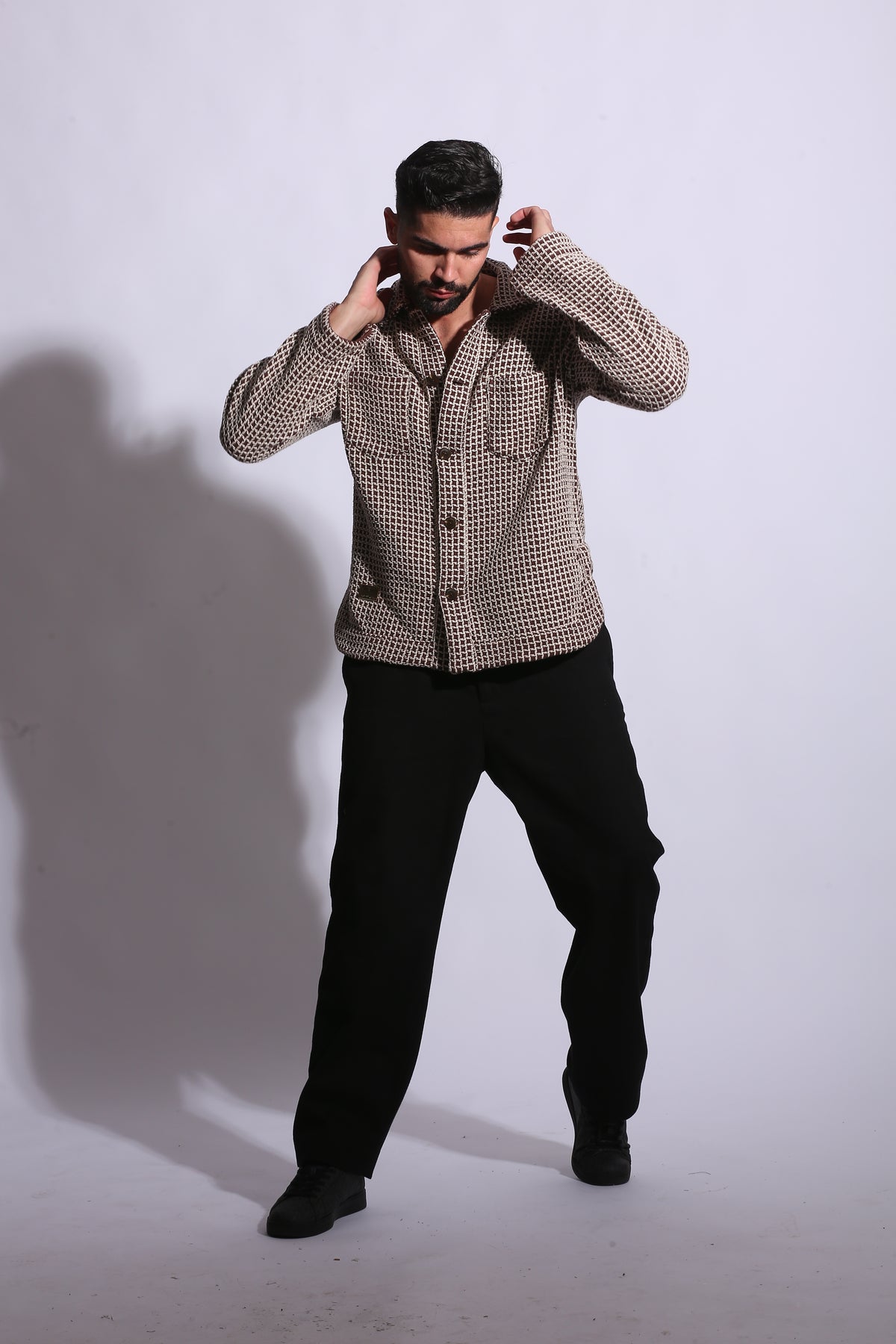 Person wearing a patterned jacket and black pants on a white background