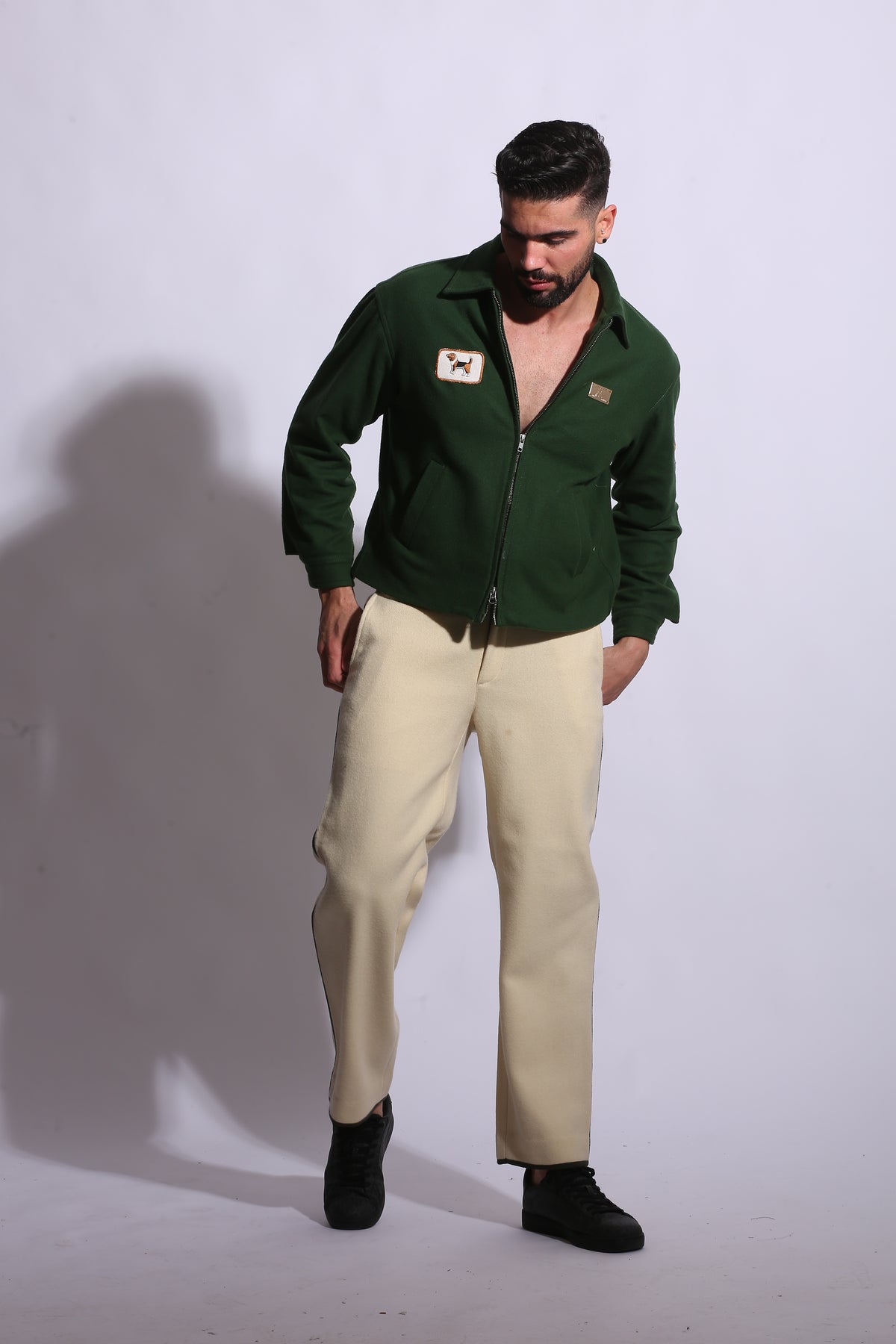 Person wearing a green jacket and beige pants on a white background
