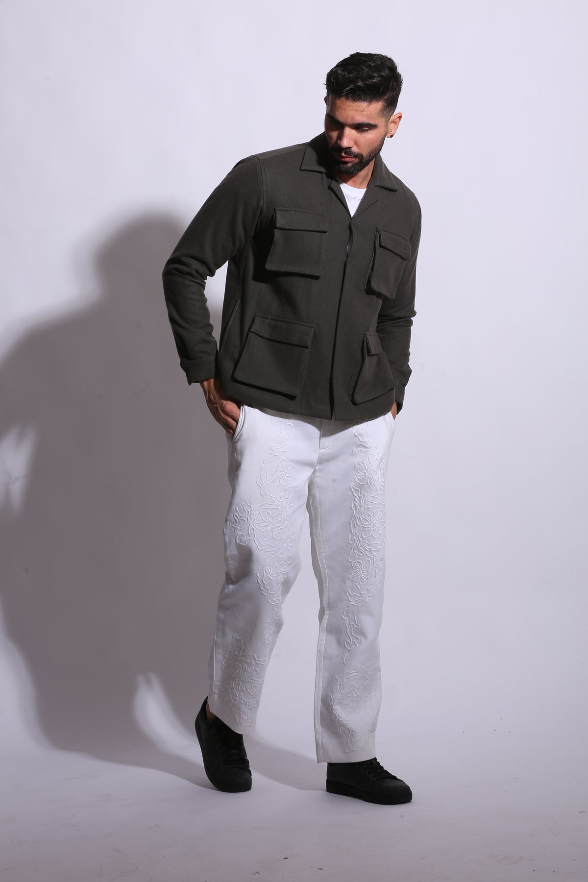 Person wearing a green jacket and white pants on a white background