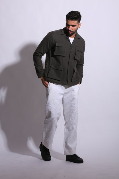 Person wearing a green jacket and white pants on a white background