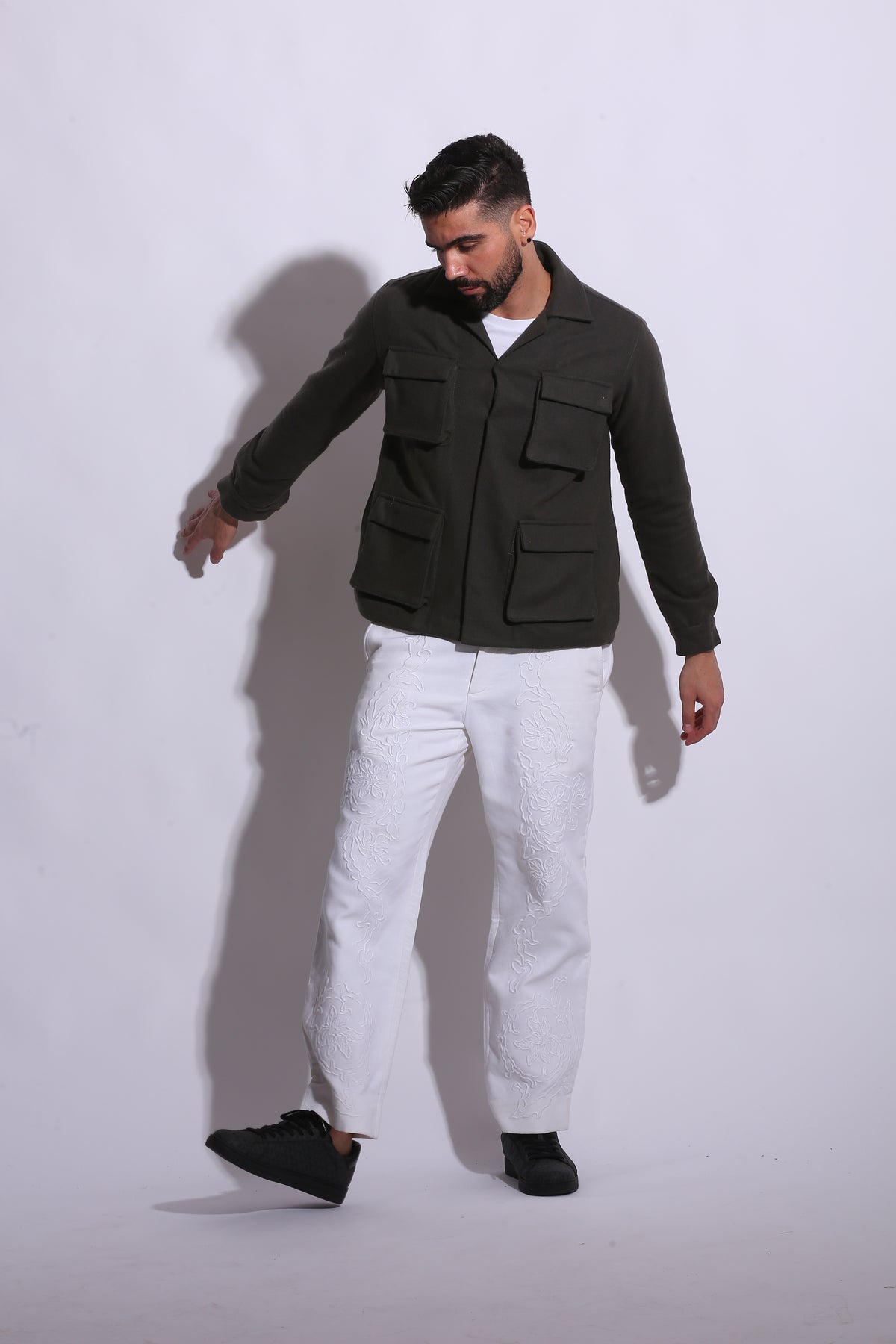 Person wearing a black jacket and white pants on a white background