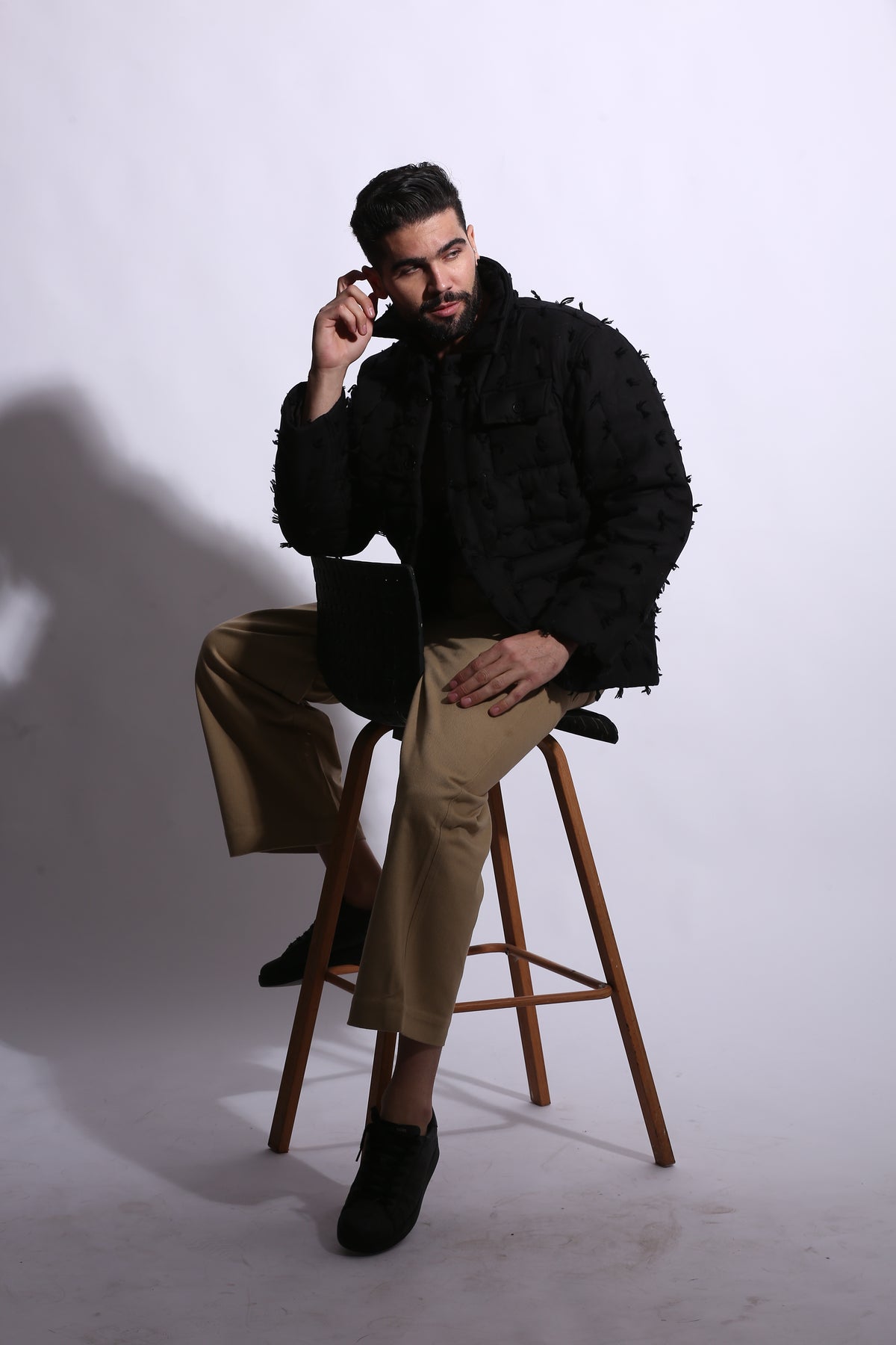 Person sitting on a stool with a white background