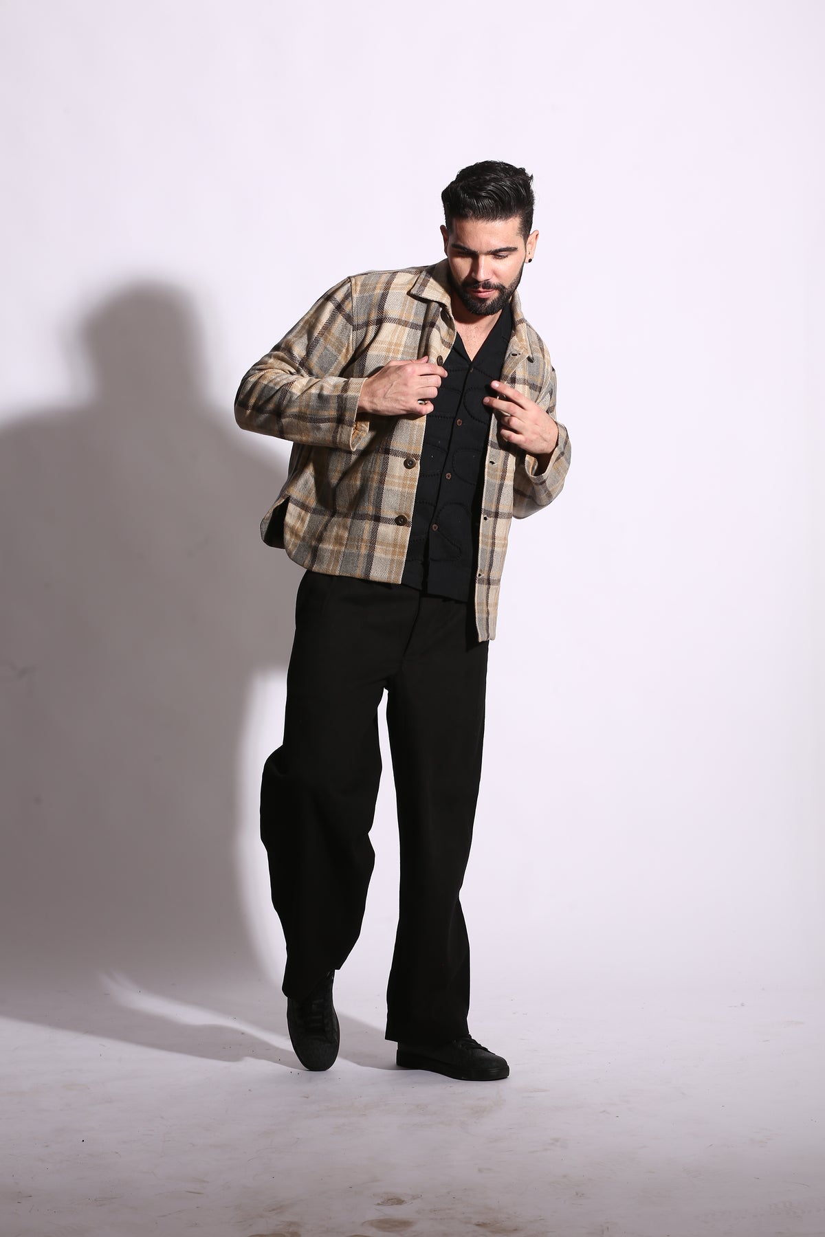 Man wearing a plaid shirt and black pants on a white background