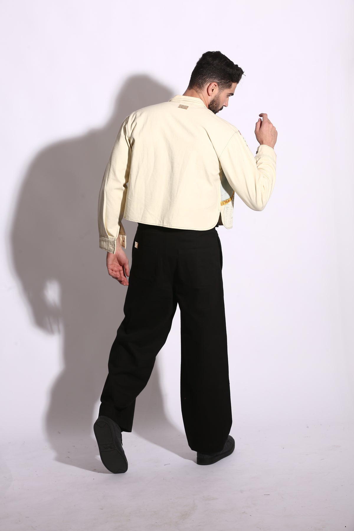 Person wearing a light-colored shirt and dark pants on a white background