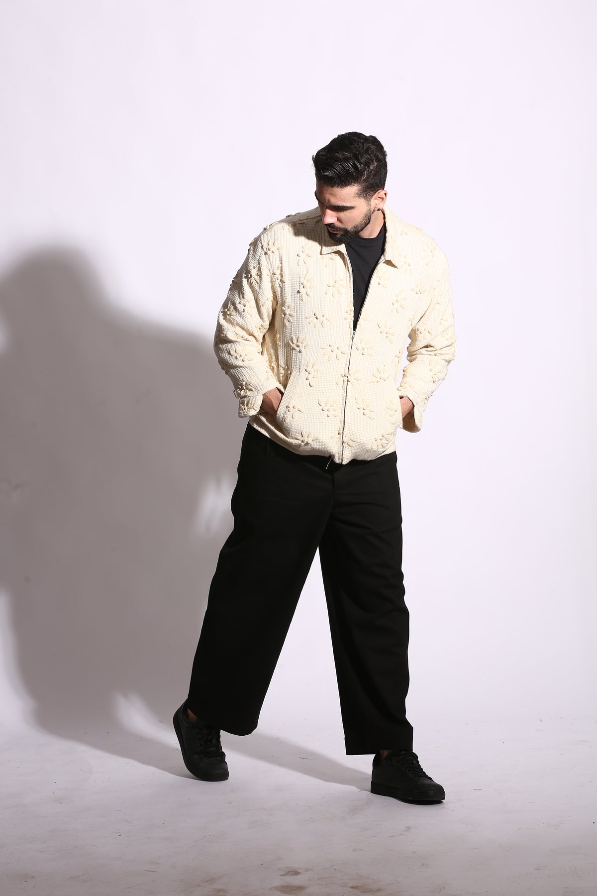 Person wearing a light-colored jacket and dark pants on a white background