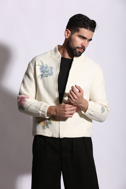 Person wearing a cream-colored sweater with floral patterns on a white background