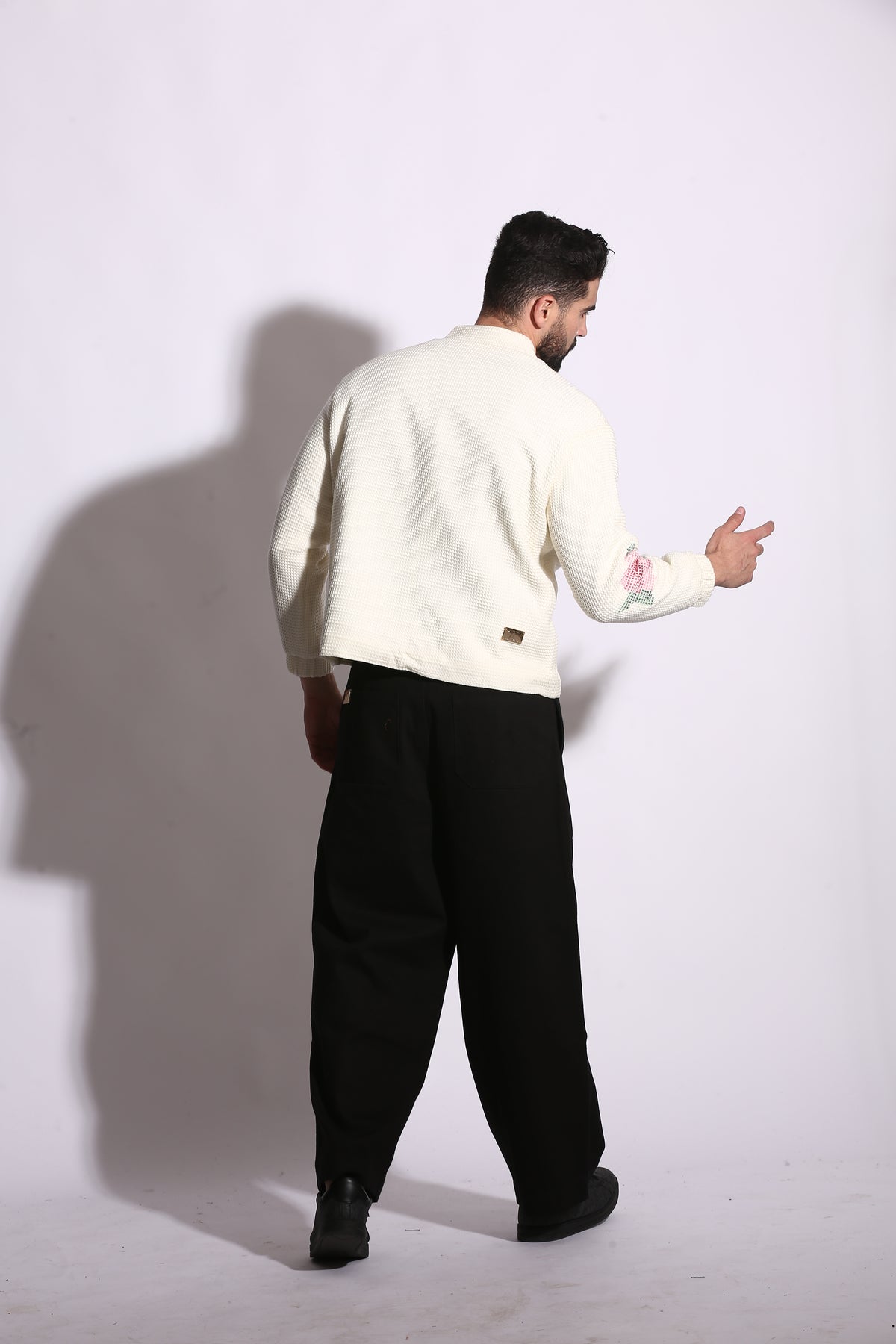Person wearing a white jacket and black pants on a white background