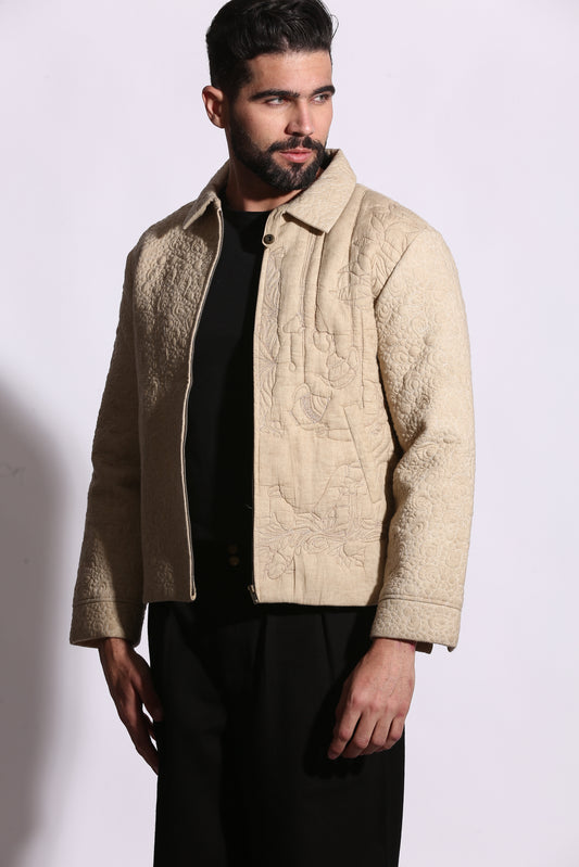 Man wearing a beige embroidered jacket on a white background