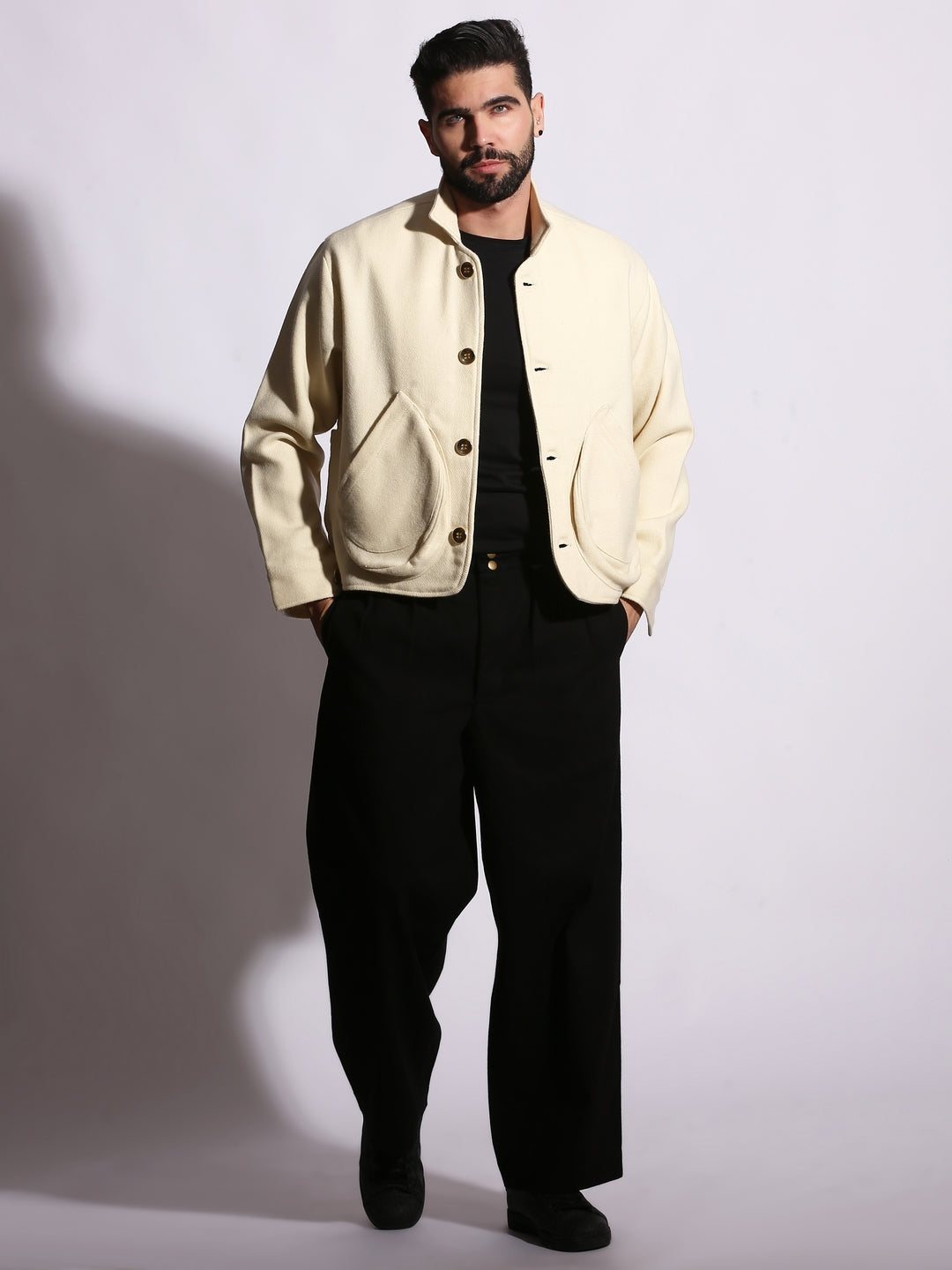 Man wearing a beige jacket and black pants against a plain background