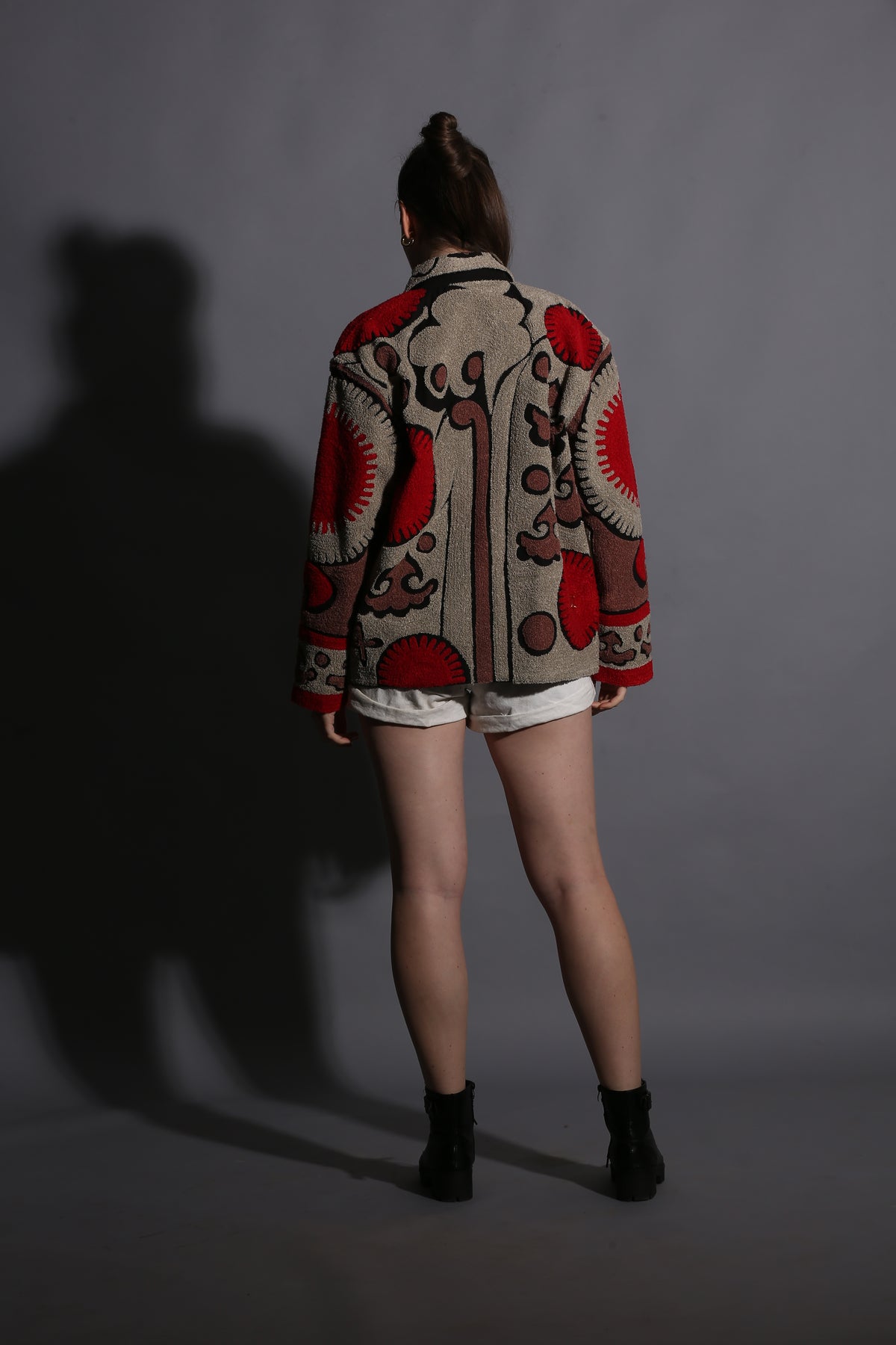 Person wearing a patterned coat on a plain background