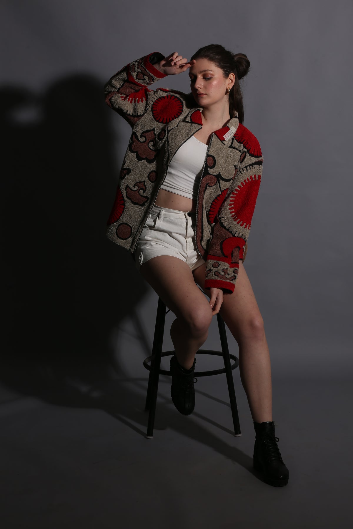 Person wearing a patterned scarf sitting on a chair against a dark background