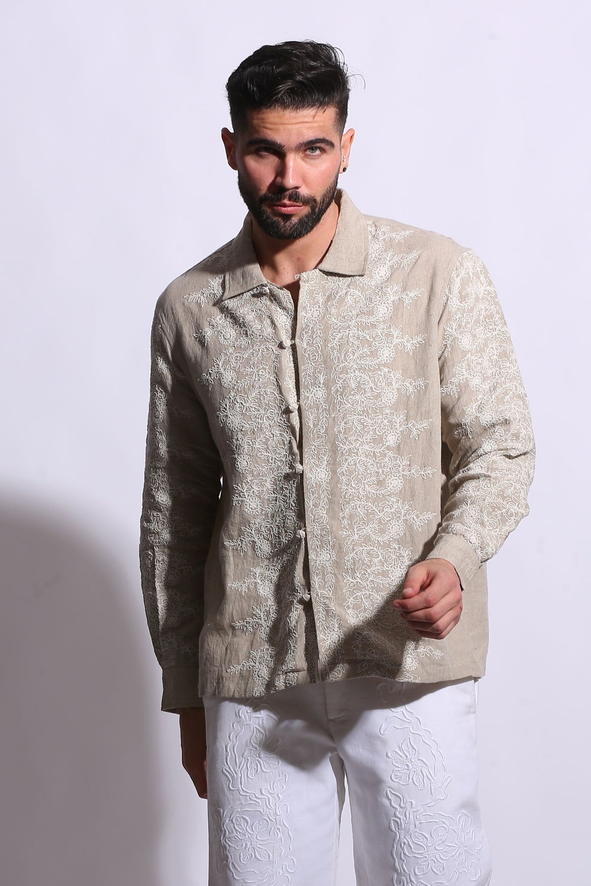 Artisanal linen shirt for men featuring a polo collar and vintage-inspired lattice embroidery in a neutral sand tone.