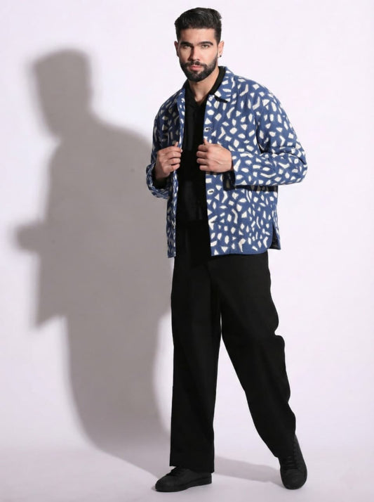 Man wearing a blue patterned jacket over a black shirt and pants on a white background