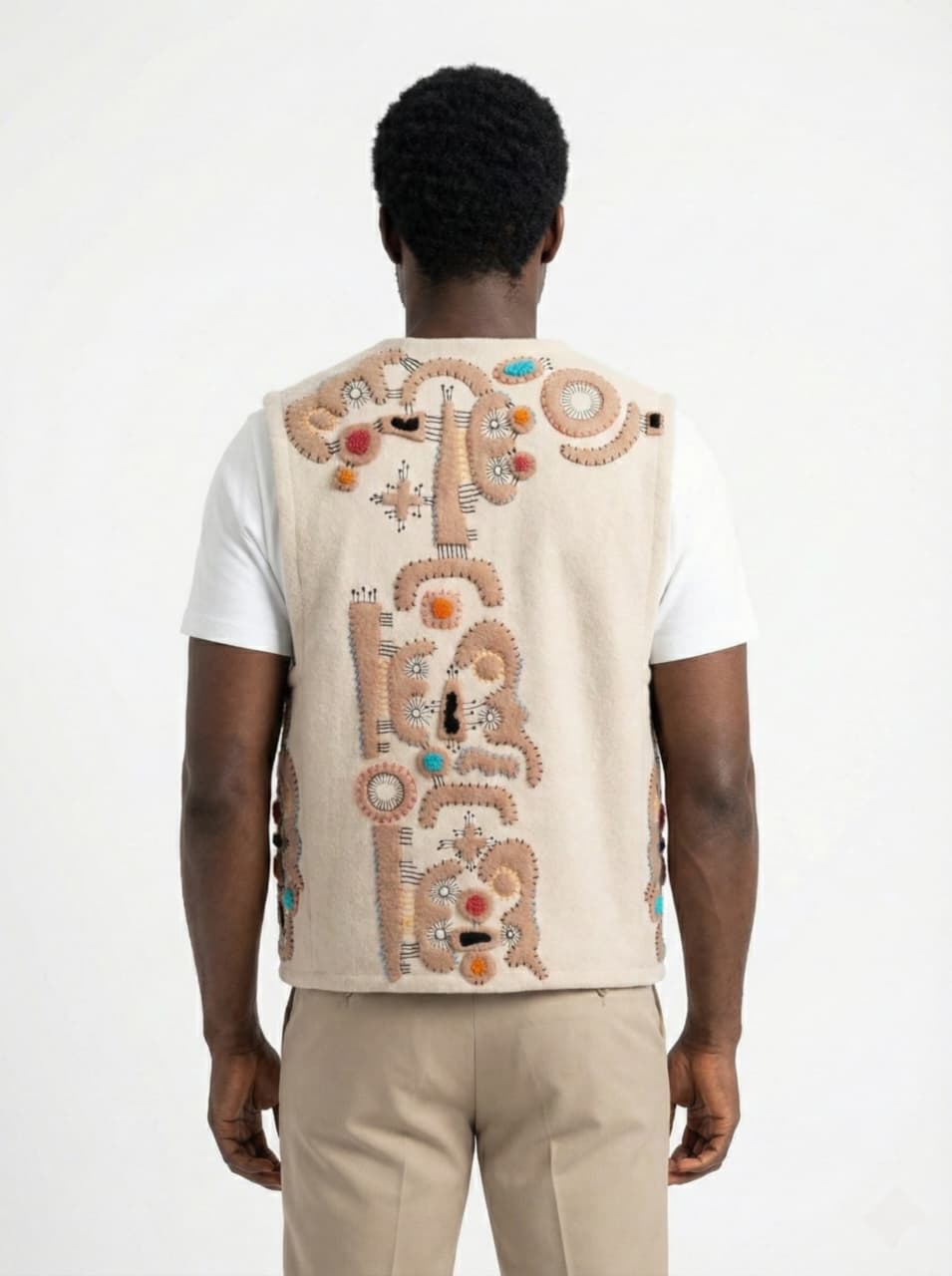 Person wearing a beige embroidered vest on a white background
