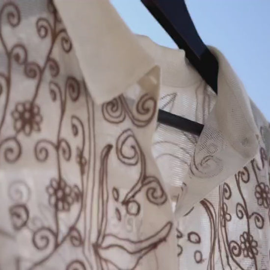 Set in a soft beige tone, the shirt is defined by its intricate chain stitch embroidery, creating a rich, textured surface that adds depth without overpowering the design.