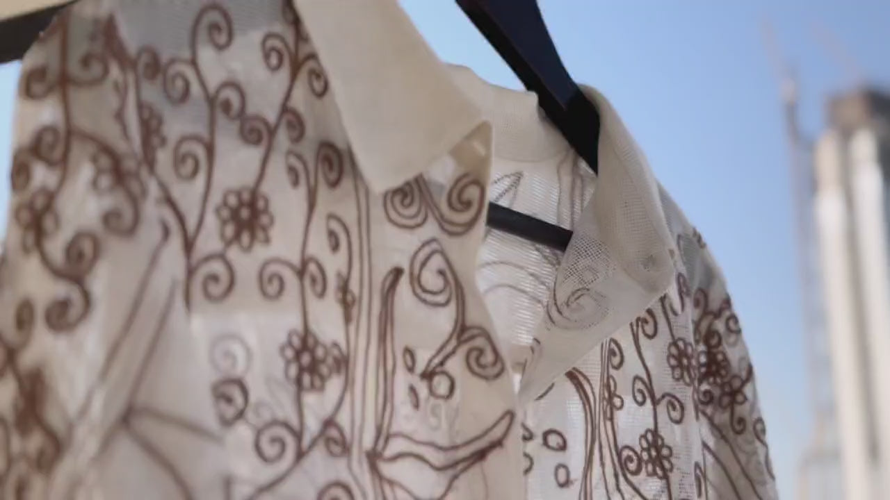 Set in a soft beige tone, the shirt is defined by its intricate chain stitch embroidery, creating a rich, textured surface that adds depth without overpowering the design.